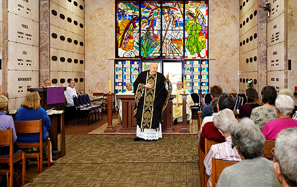 Father Ralph Argentino delivers a brief homily to a near capacity crowd during the inaugural Month's Mind Mass in the Chapel of the Resurrection at Calvary Catholic Cemetery Jan. 26. Deacons Paul Haber and John Buckley assisted at the altar and Jo Greene, Assistant Coordinator of Music for the Cathedral of St. Jude the Apostle, served as cantor and organist.